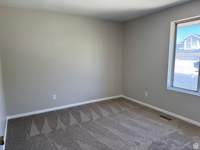 carpeted empty room featuring baseboards