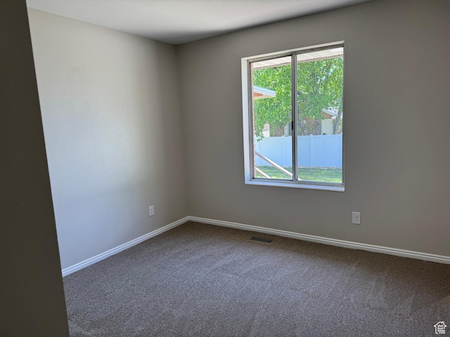 empty room with dark carpet, healthy amount of natural light, and baseboards