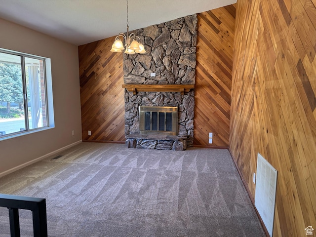 unfurnished living room featuring baseboards, wooden walls, a chandelier, a fireplace, and carpet