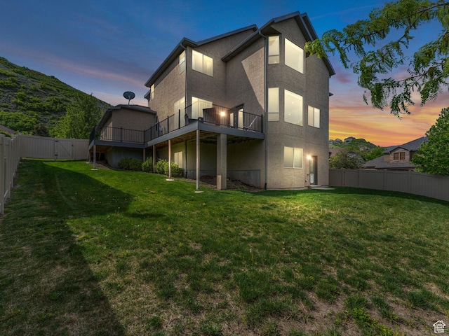 back of property at dusk with stucco siding and a deck