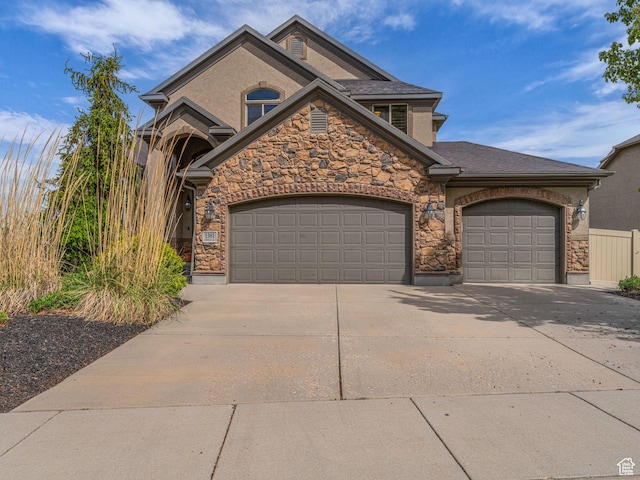 view of front facade featuring an attached garage, stone siding, and driveway