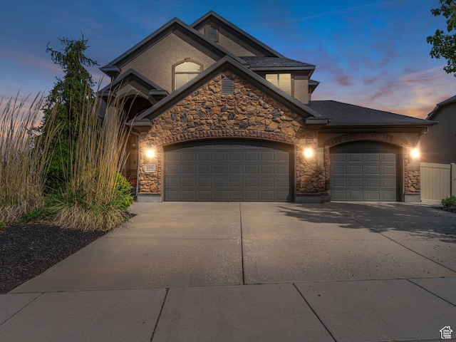 view of front of house featuring stone siding, driveway, and a garage