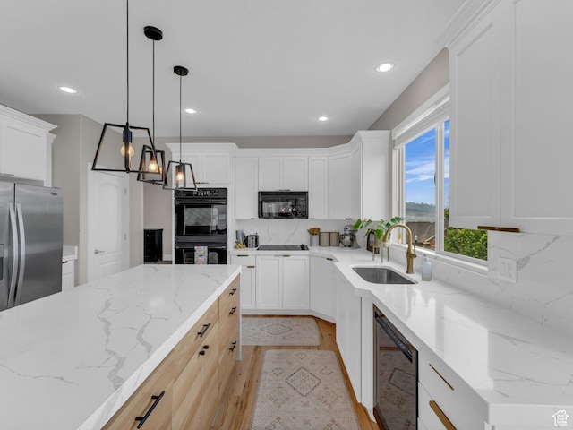 kitchen featuring a sink, black appliances, backsplash, light wood finished floors, and white cabinetry