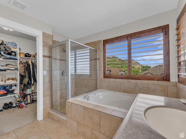 full bath featuring a stall shower, tile patterned flooring, a spacious closet, and a sink