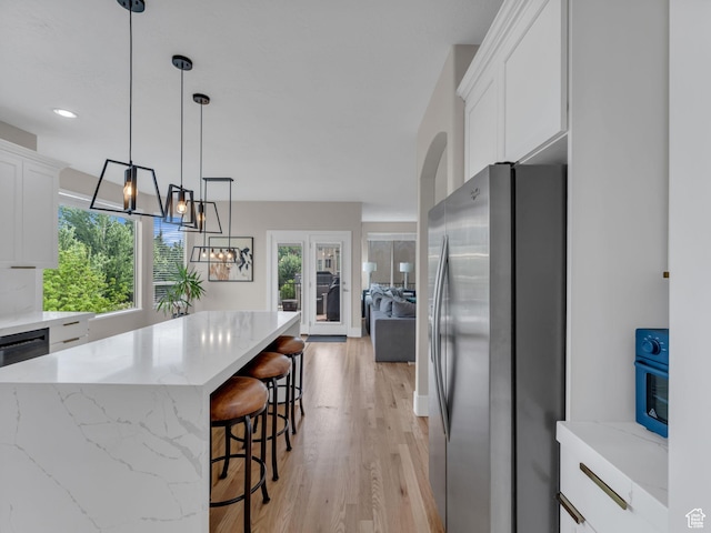 kitchen featuring freestanding refrigerator, white cabinetry, light wood-style flooring, and light stone counters