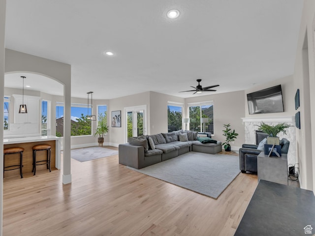 living room featuring light wood-style floors, baseboards, a ceiling fan, plenty of natural light, and recessed lighting
