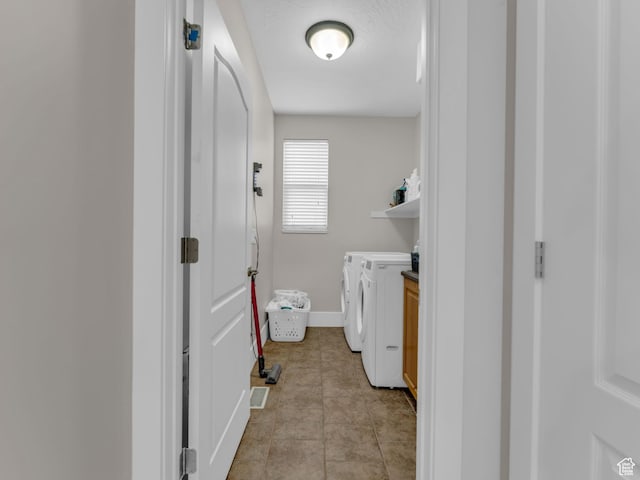 laundry area featuring washing machine and clothes dryer, baseboards, and light tile patterned flooring