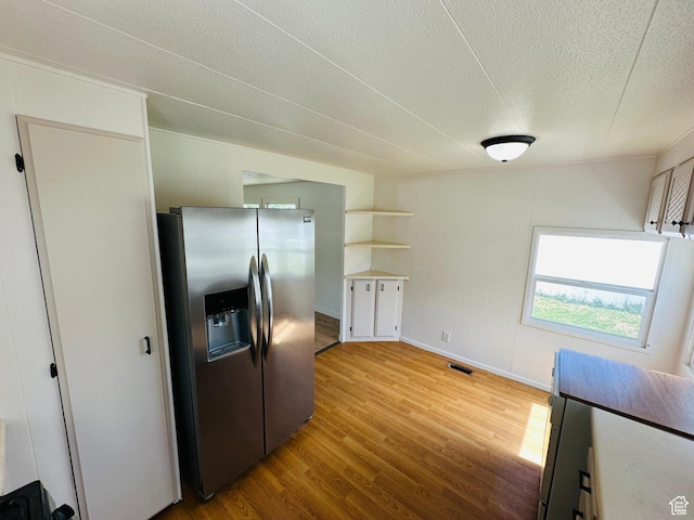 kitchen featuring stainless steel fridge, wood finished floors, a textured ceiling, open shelves, and baseboards