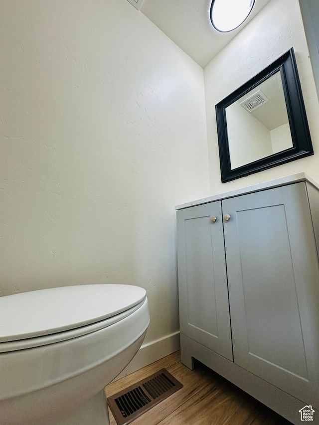 half bath with wood finished floors, baseboards, and toilet