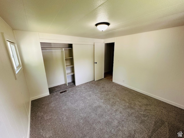 unfurnished bedroom with carpet, a closet, and baseboards
