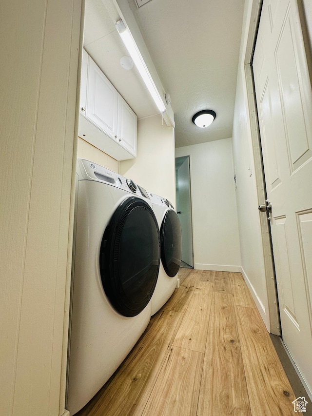 laundry area with cabinet space, light wood-style floors, washer and clothes dryer, and baseboards