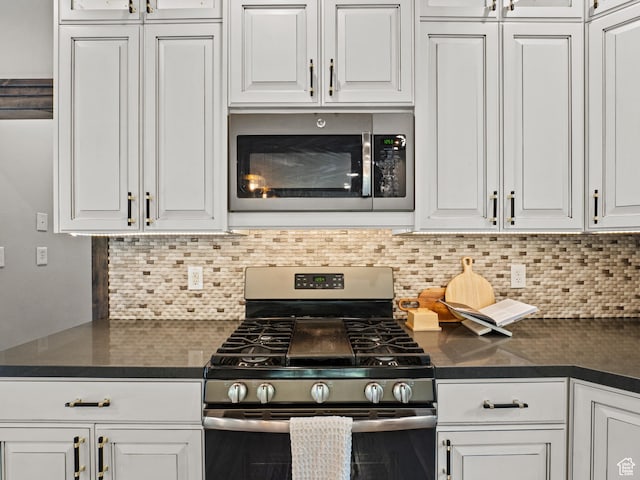 kitchen featuring stainless steel appliances, dark countertops, and white cabinetry