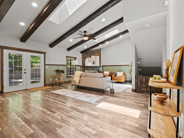 living room with a skylight, wood finished floors, ceiling fan, french doors, and recessed lighting