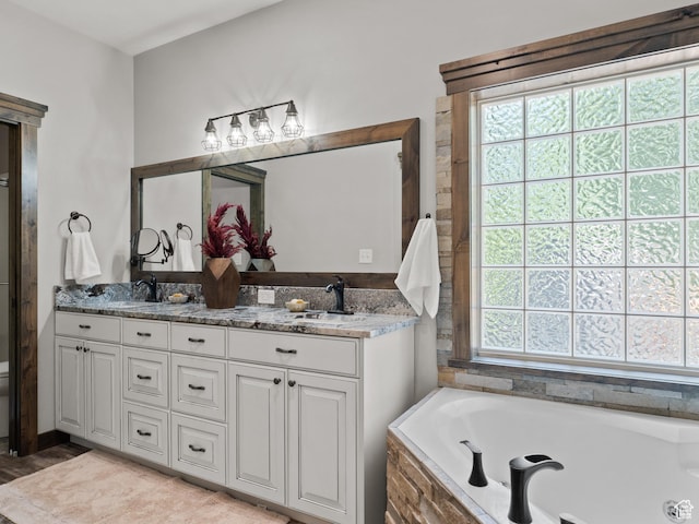 bathroom with a garden tub, double vanity, and wood finished floors