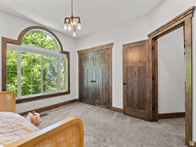 carpeted bedroom featuring a chandelier and baseboards