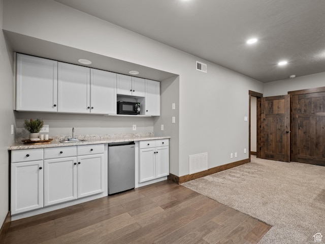 kitchen with dishwashing machine, black microwave, white cabinets, wood finished floors, and baseboards