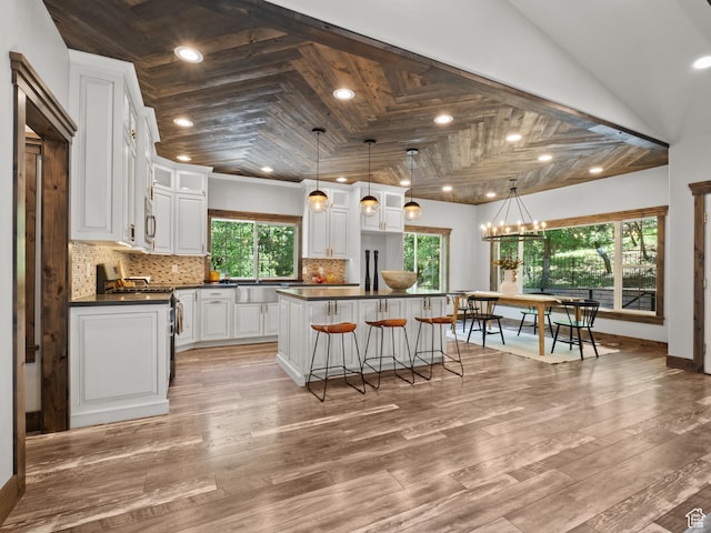 kitchen with dark countertops, stainless steel range with gas cooktop, backsplash, white cabinets, and recessed lighting