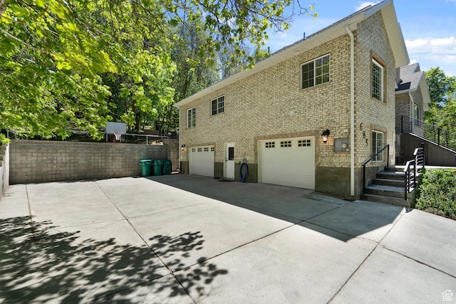 view of side of property with an attached garage, concrete driveway, and brick siding