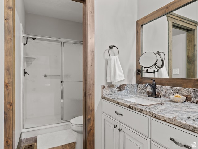 bathroom with a stall shower, toilet, and vanity