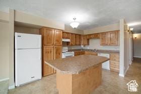 kitchen with freestanding refrigerator, range, a kitchen island, and brown cabinets