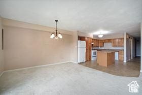 kitchen with refrigerator, open floor plan, brown cabinetry, baseboards, and a kitchen island