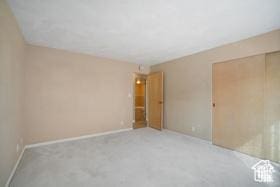 spare room featuring light colored carpet and baseboards