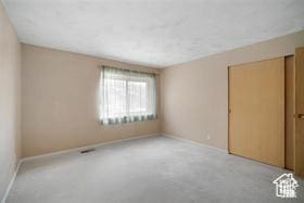 spare room featuring light colored carpet and baseboards