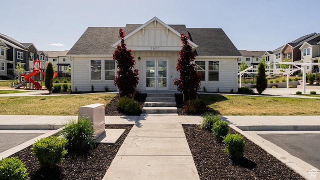 view of front facade with french doors, board and batten siding, a front lawn, and a residential view
