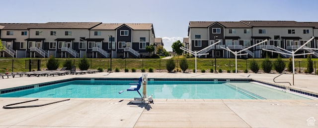 community pool featuring fence, a residential view, and a patio