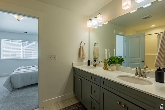 ensuite bathroom with tile patterned floors, baseboards, and double vanity