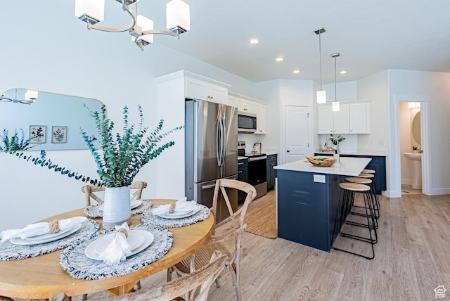 kitchen featuring stainless steel appliances, a chandelier, white cabinetry, light wood-style floors, and recessed lighting