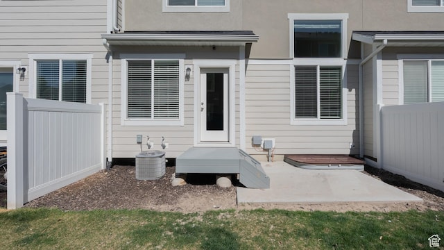 entrance to property with fence, central AC unit, a patio, and stucco siding