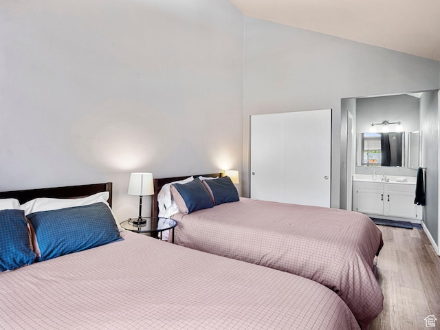 bedroom featuring wood finished floors, high vaulted ceiling, and ensuite bathroom