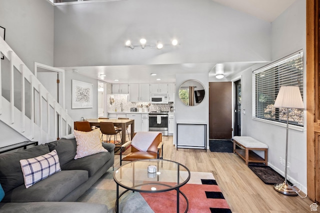 living area featuring light wood finished floors, stairs, and baseboards