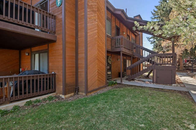 view of side of property featuring a yard, stairway, and a wooden deck