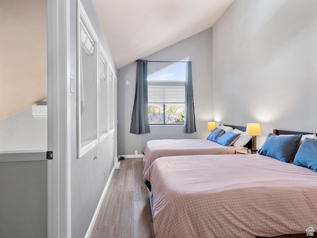 bedroom featuring lofted ceiling, wood finished floors, and baseboards