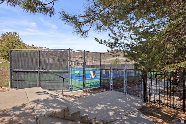 view of tennis court with a gate and fence