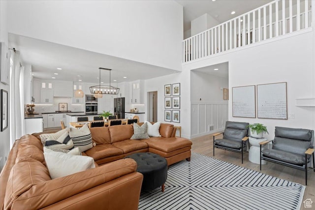 13741 S 3870 W, Riverton, UT 84065 - living area featuring light wood-style floors, a chandelier, recessed lighting, a high ceiling, and a wainscoted wall