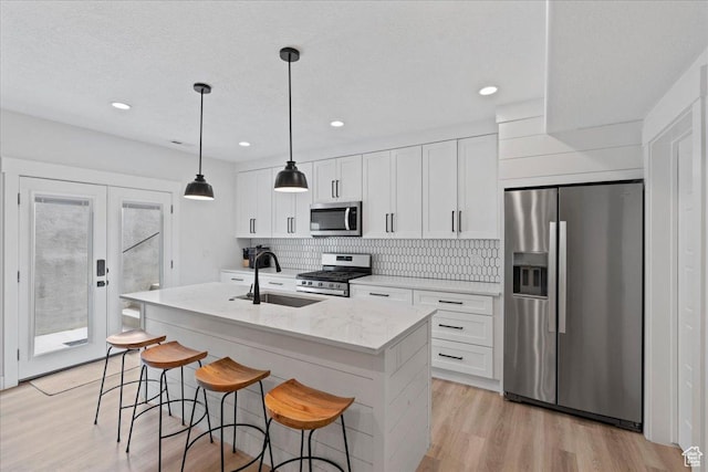 13741 S 3870 W, Riverton, UT 84065 - kitchen with stainless steel appliances, a sink, a kitchen island with sink, decorative backsplash, and white cabinetry