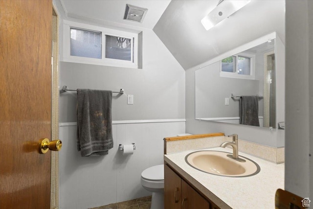 bathroom with toilet, lofted ceiling, vanity, and a wainscoted wall