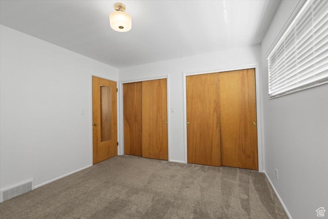 unfurnished bedroom featuring multiple closets, carpet floors, and baseboards