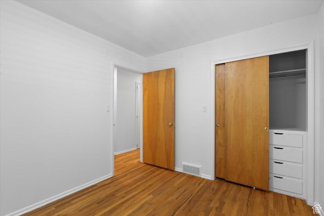 unfurnished bedroom with wood finished floors, a closet, and baseboards