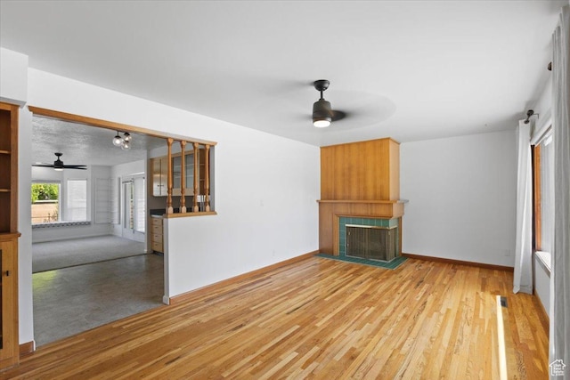 unfurnished living room with a ceiling fan, a fireplace, and wood finished floors