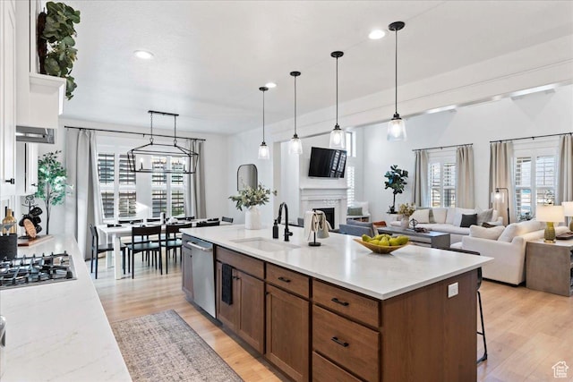 kitchen with a sink, appliances with stainless steel finishes, open floor plan, a fireplace, and recessed lighting