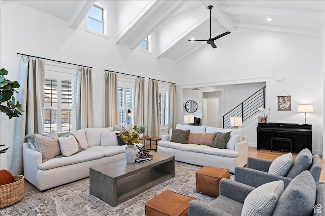 living area with high vaulted ceiling, healthy amount of natural light, beamed ceiling, stairs, and wood finished floors