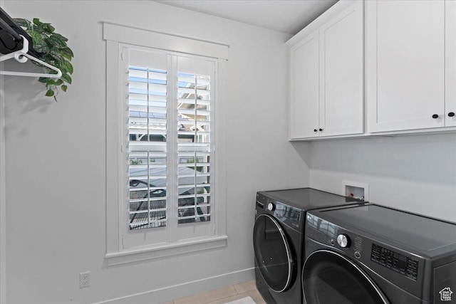 clothes washing area with cabinet space, washing machine and clothes dryer, baseboards, and tile patterned floors