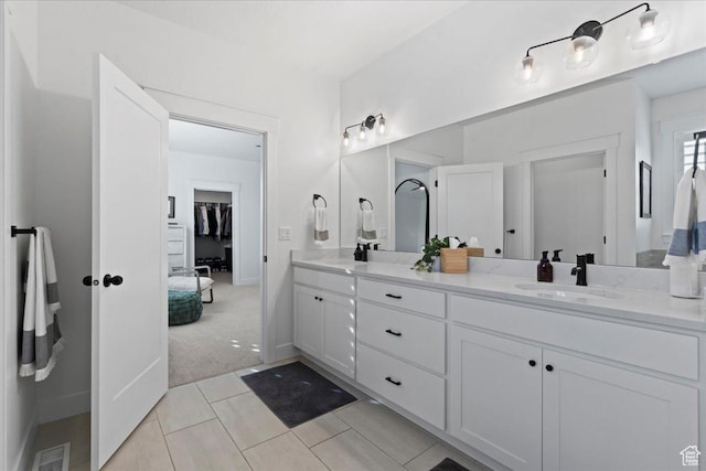 bathroom featuring double vanity, tile patterned floors, and a walk in closet