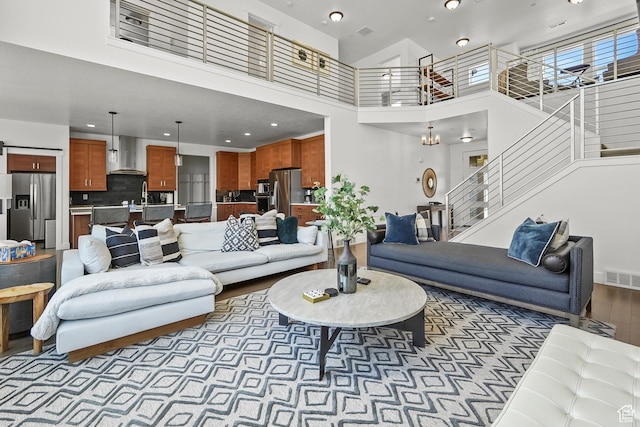 living room featuring a towering ceiling, stairs, wood finished floors, recessed lighting, and baseboards