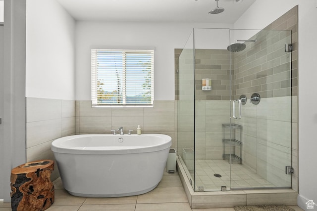 bathroom with a stall shower, a freestanding bath, tile patterned flooring, tile walls, and wainscoting