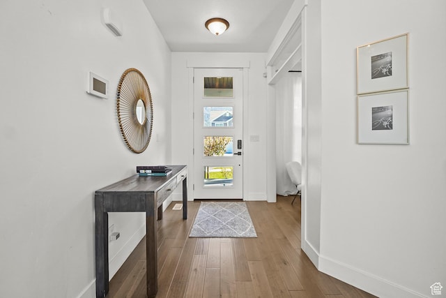 doorway to outside featuring baseboards and wood finished floors
